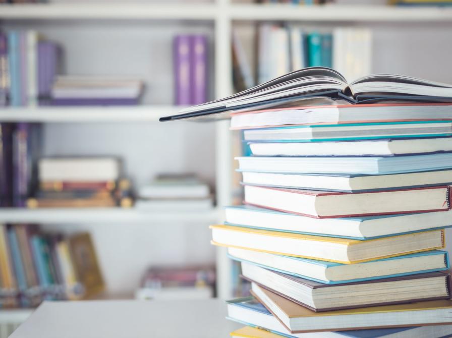 Bøger i en bunke og bøger i baggrunden på hylder